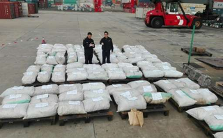 Customs officers stand guard over seized pangolin scales at a port in Shanghai. (Image: AFP/CCTV)